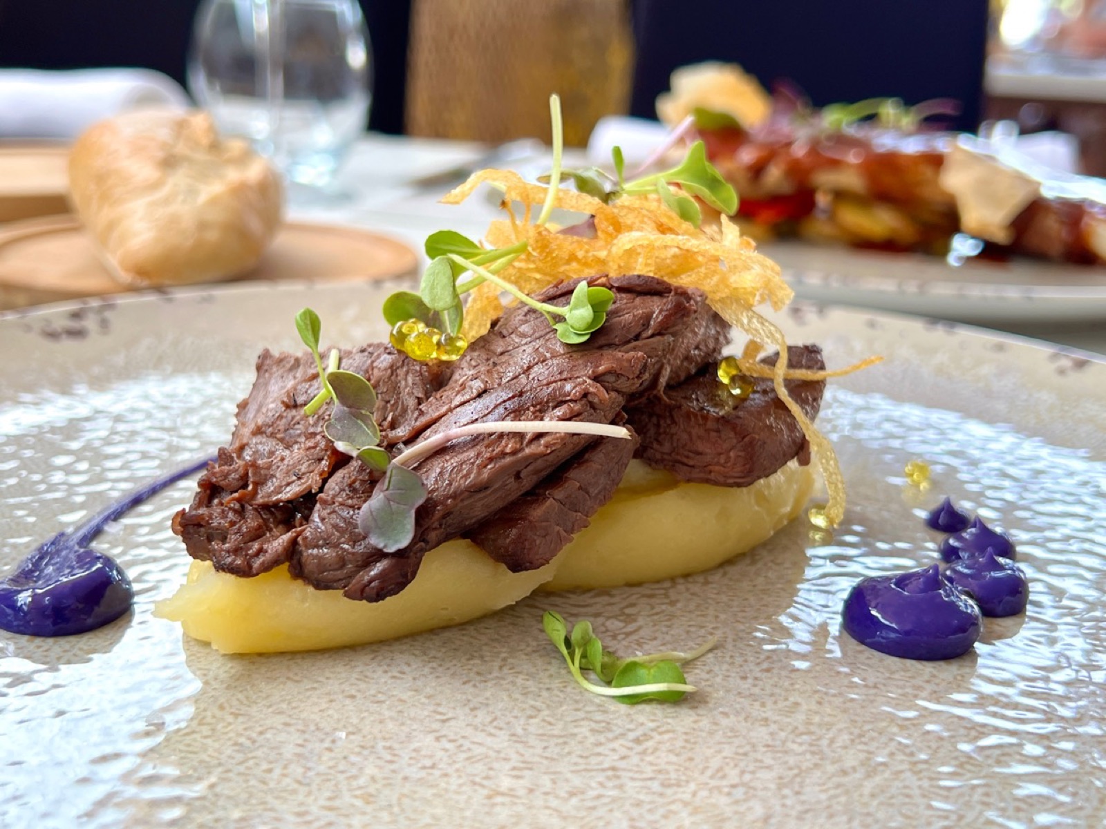 Carne con pure y salsa servida en Essencia